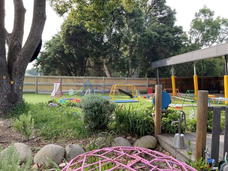 A wooden fence features a circular mandala-like design with painted rings and attached reflective discs, centered on overlapping boards.
